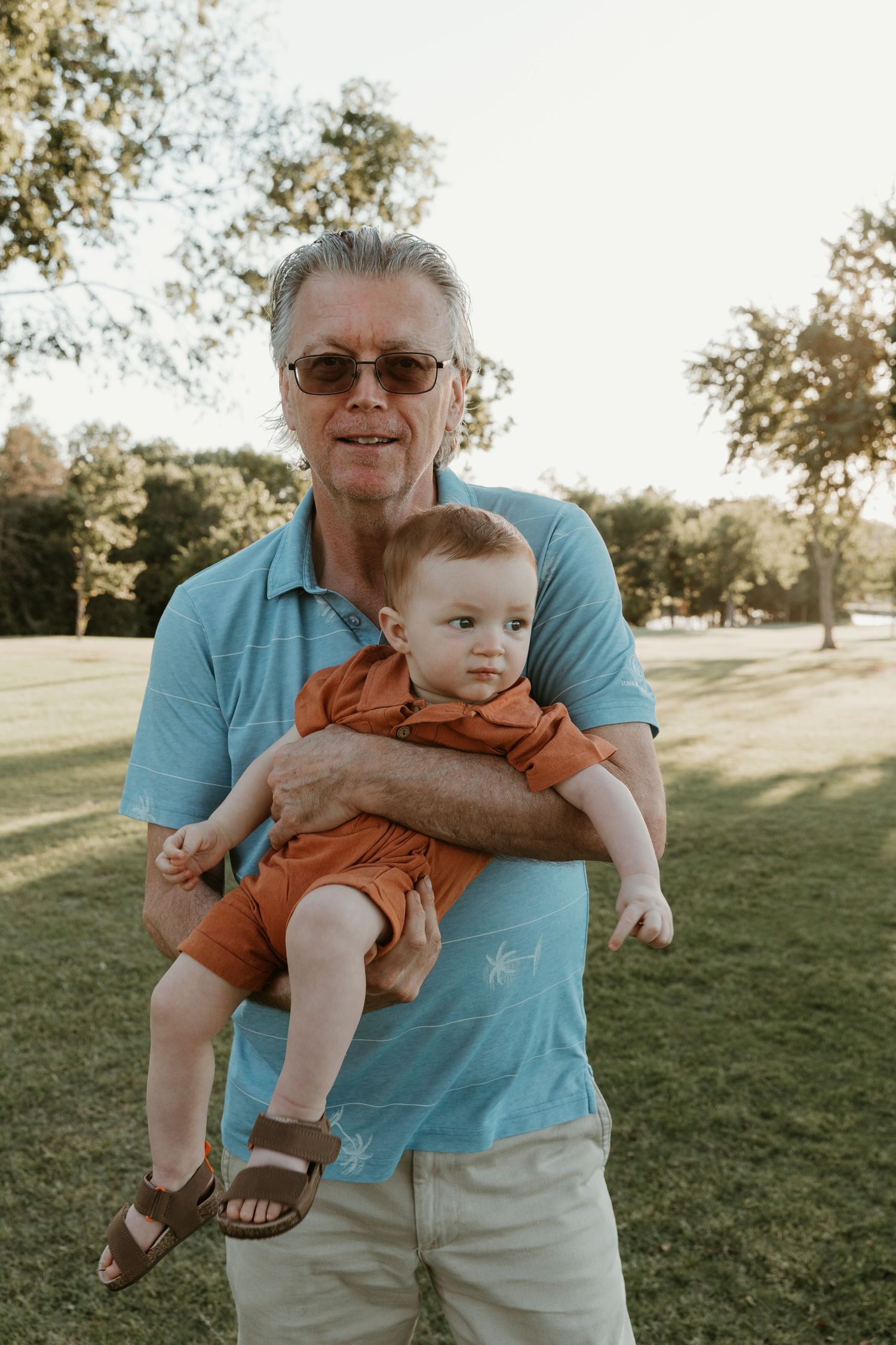 A heartwarming moment between a young child and older adult in a park setting.
