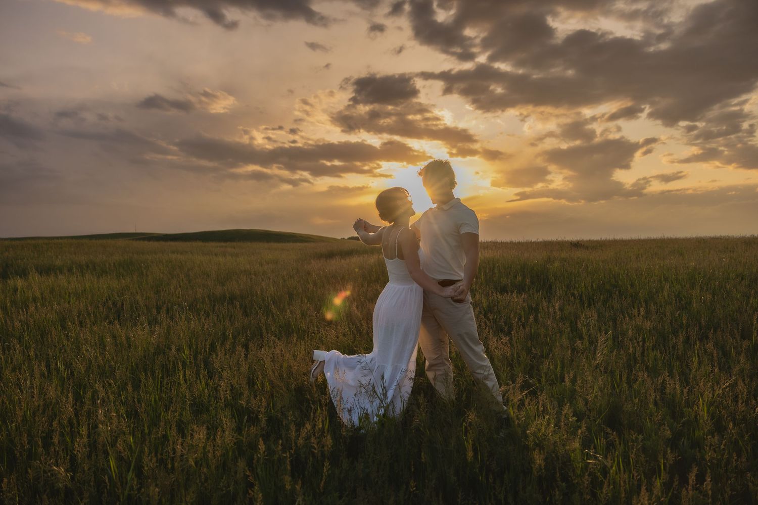 A silhouetted couple dances in a golden wheat field at sunset, near Okotoks, Alberta.