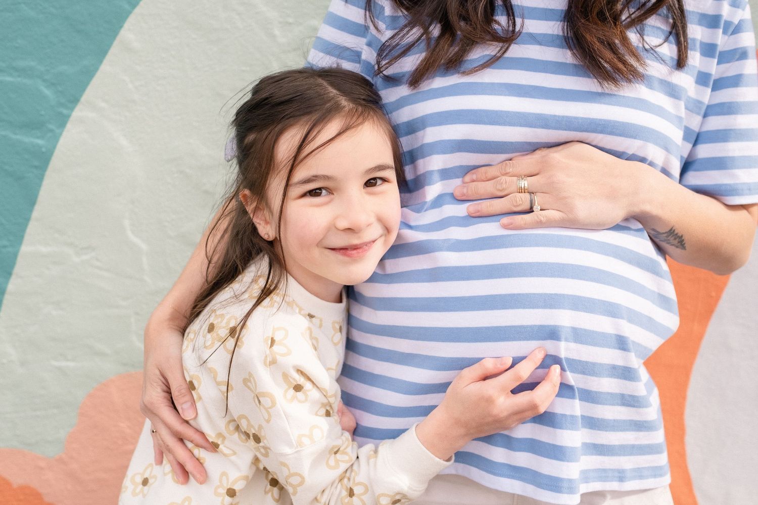 A touching moment captured against a turquoise and coral colored wall background.