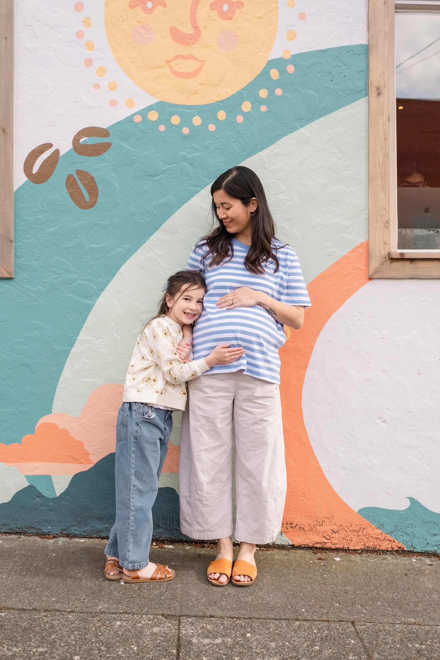 Sweet interactions against a colorful mural featuring a sun and abstract designs.