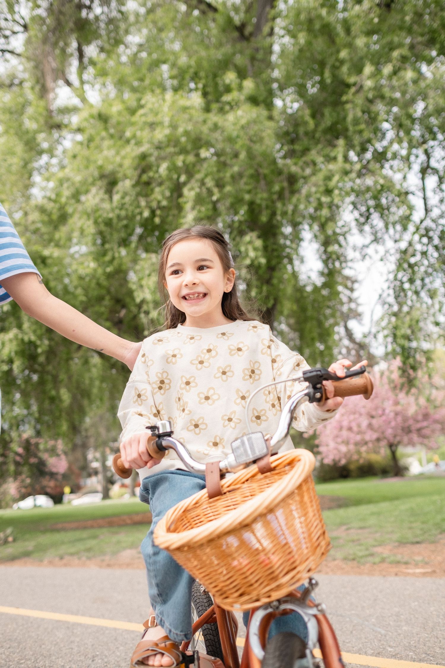 A joyful moment captured on a bicycle with a woven basket along a peaceful park path.