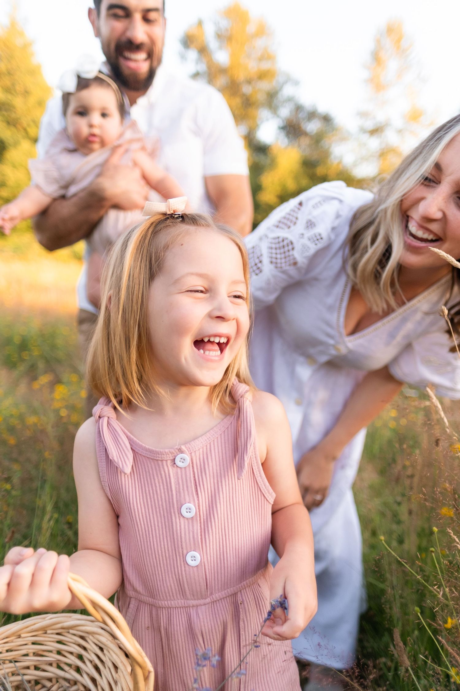 A joyful family plays together in a sunlit field during golden hour, creating candid moments of laughter and fun.