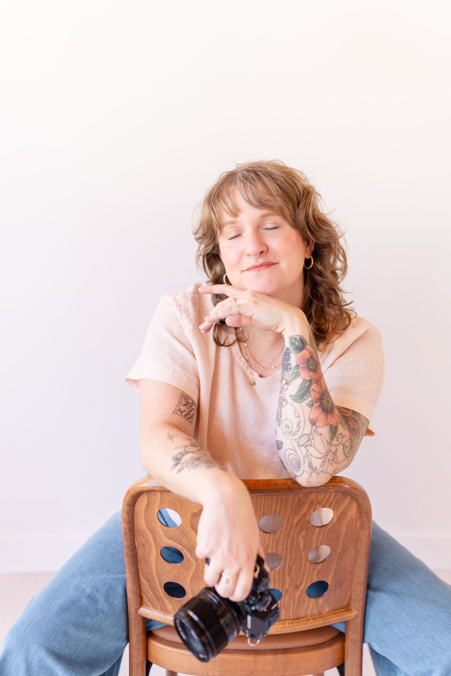 A person wearing a tan knit sweater sits with closed eyes in a contemplative pose against a white background.