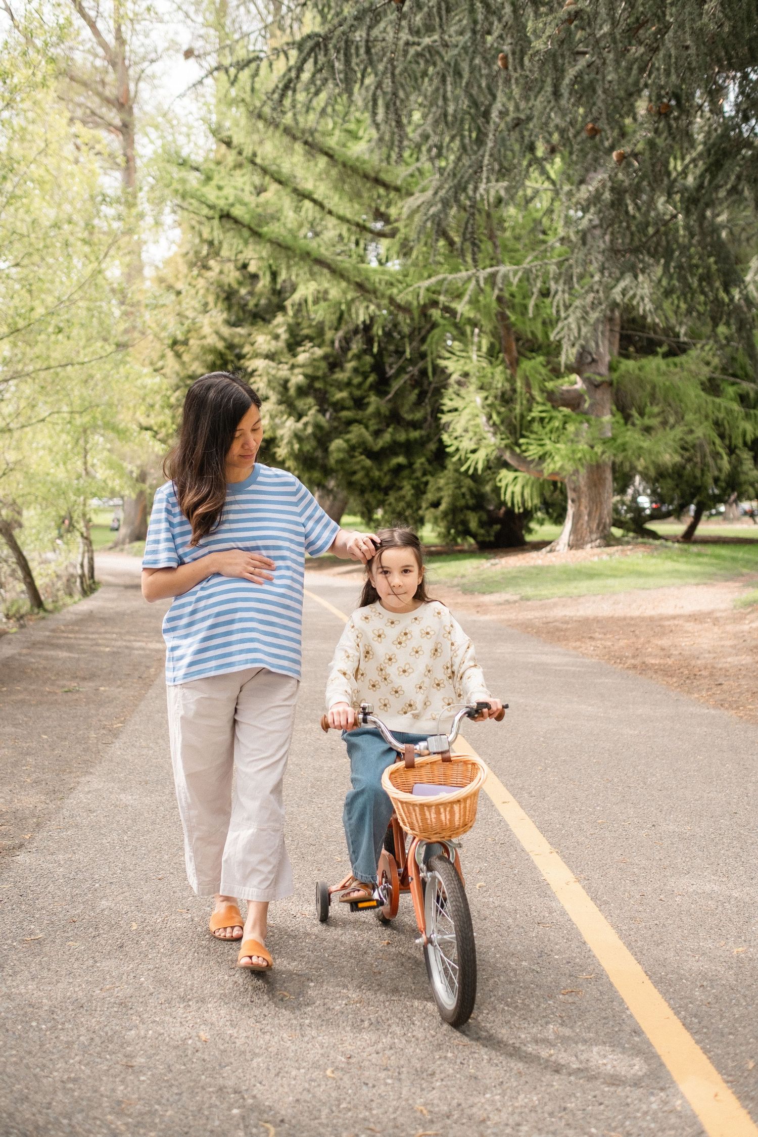 A leisurely walk alongside a bicycle on a tree-lined path in a park on a sunny afternoon.