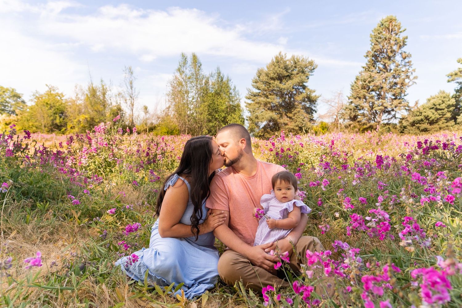 Family poses together in a beautiful meadow filled with vibrant pink wildflowers during golden hour.