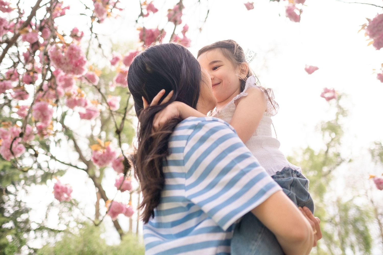 Candid moments of affection captured beneath flowering cherry trees in springtime.