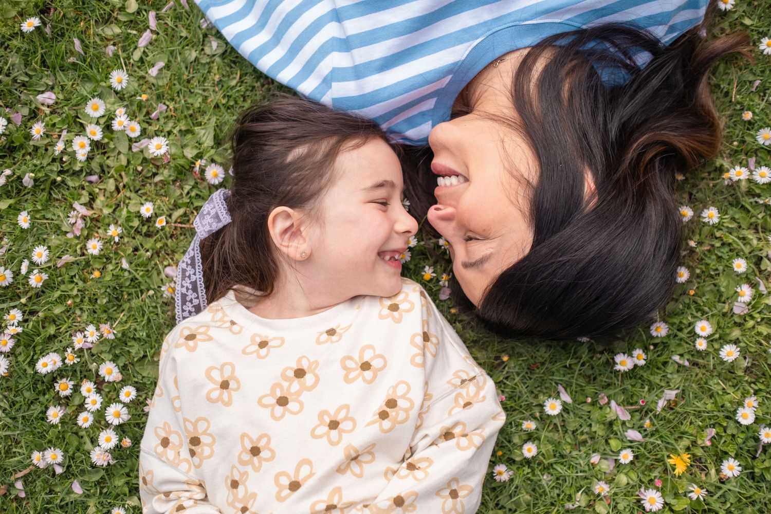 A couple lying in a field of daisies shares joyful laughter together in a series of candid moments.
