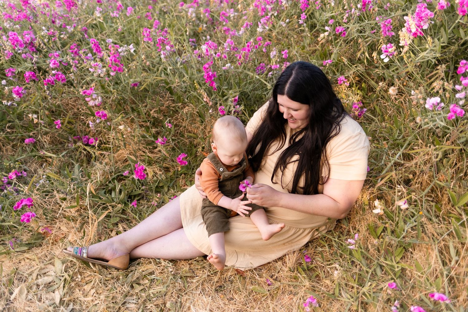 Two people sitting in a field of pink wildflowers enjoying a tender moment together.