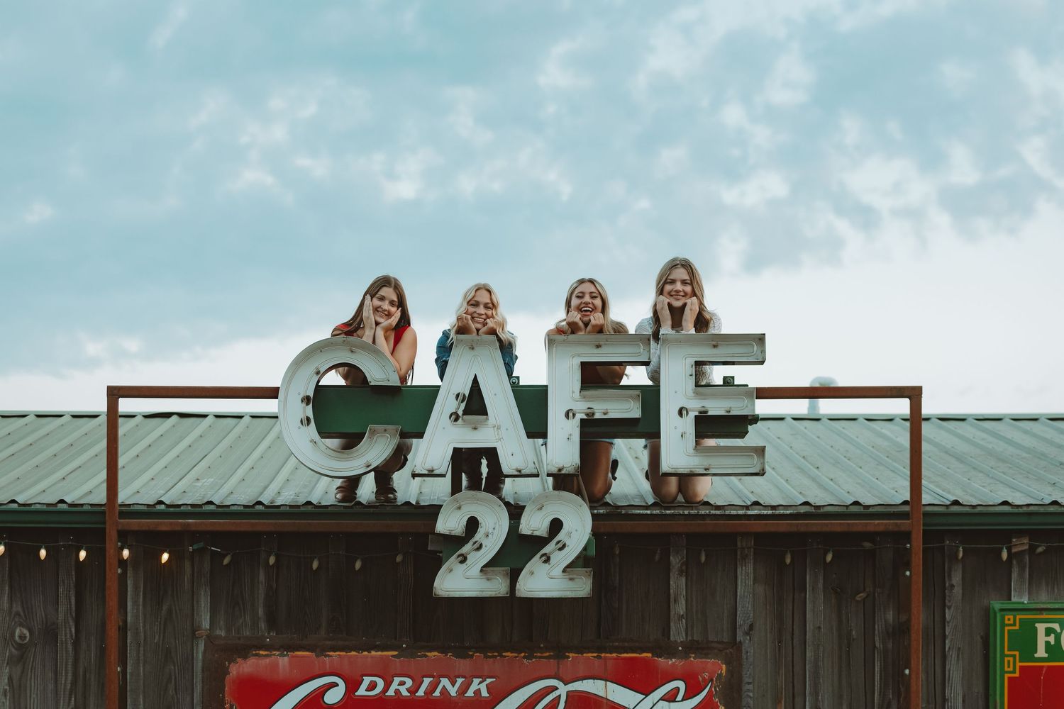 Retro cafe exterior with vintage signage and decorative lighting against blue sky.