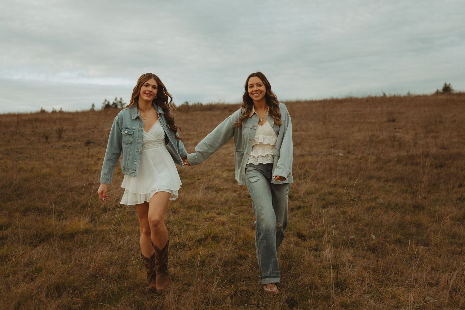 Two people in casual outfits share a joyful moment while walking through a brown autumn field.