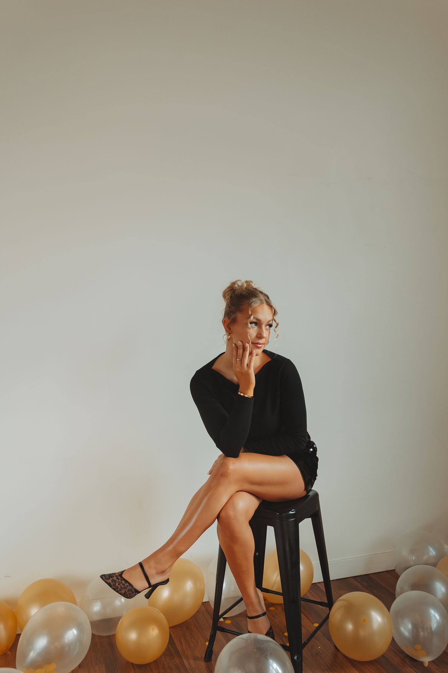 Artistic portrait series with balloons showing a person in black seated on a chair against neutral background.