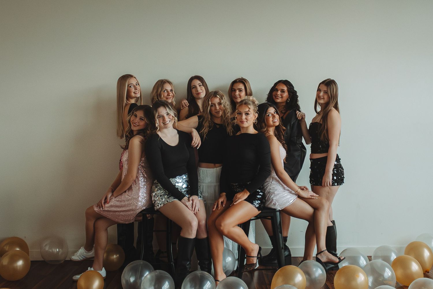 Group of friends posing together with balloons in a casual indoor setting.