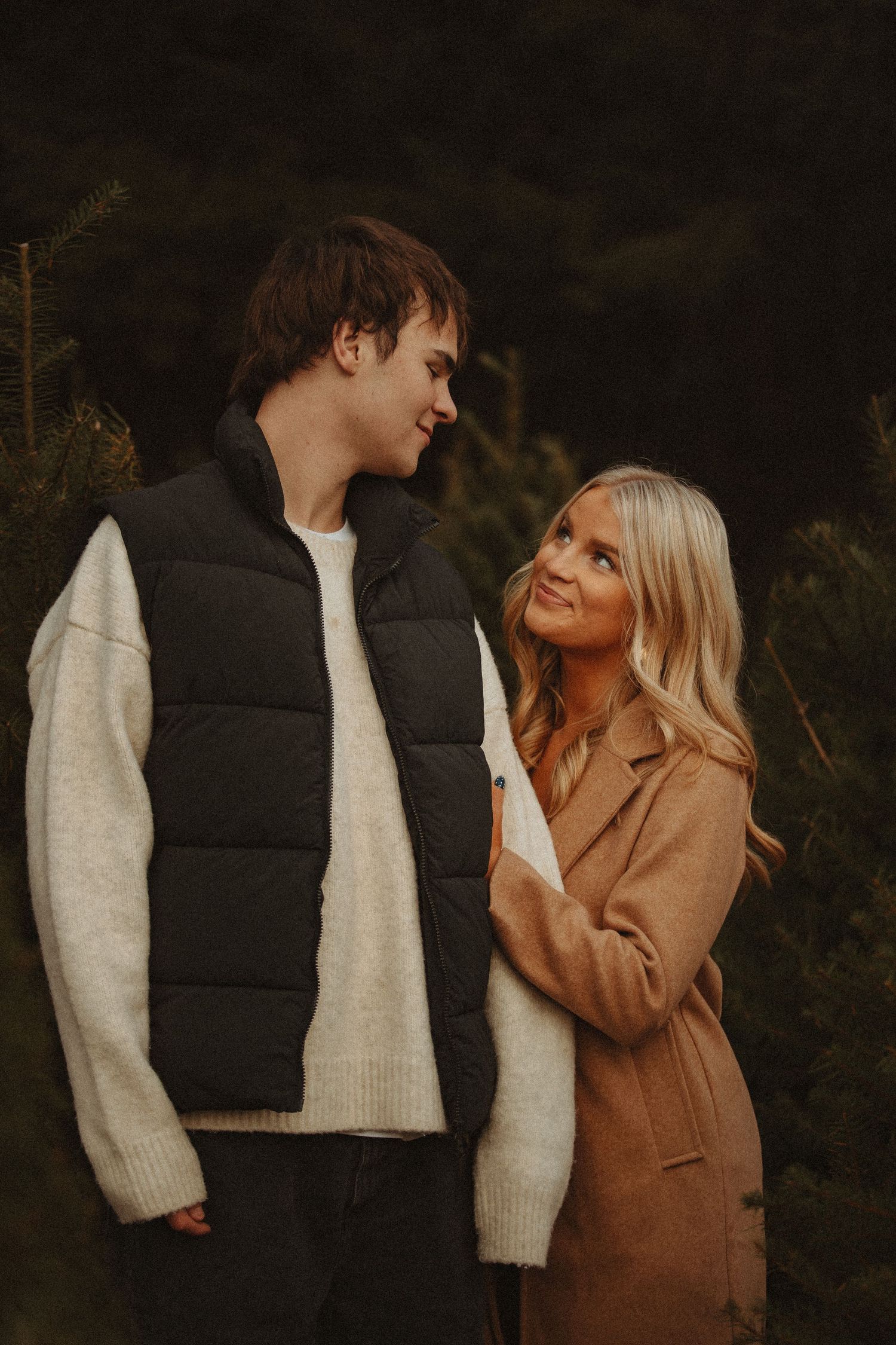 A couple in autumn attire share intimate moments against a dark background in a series of romantic photos.