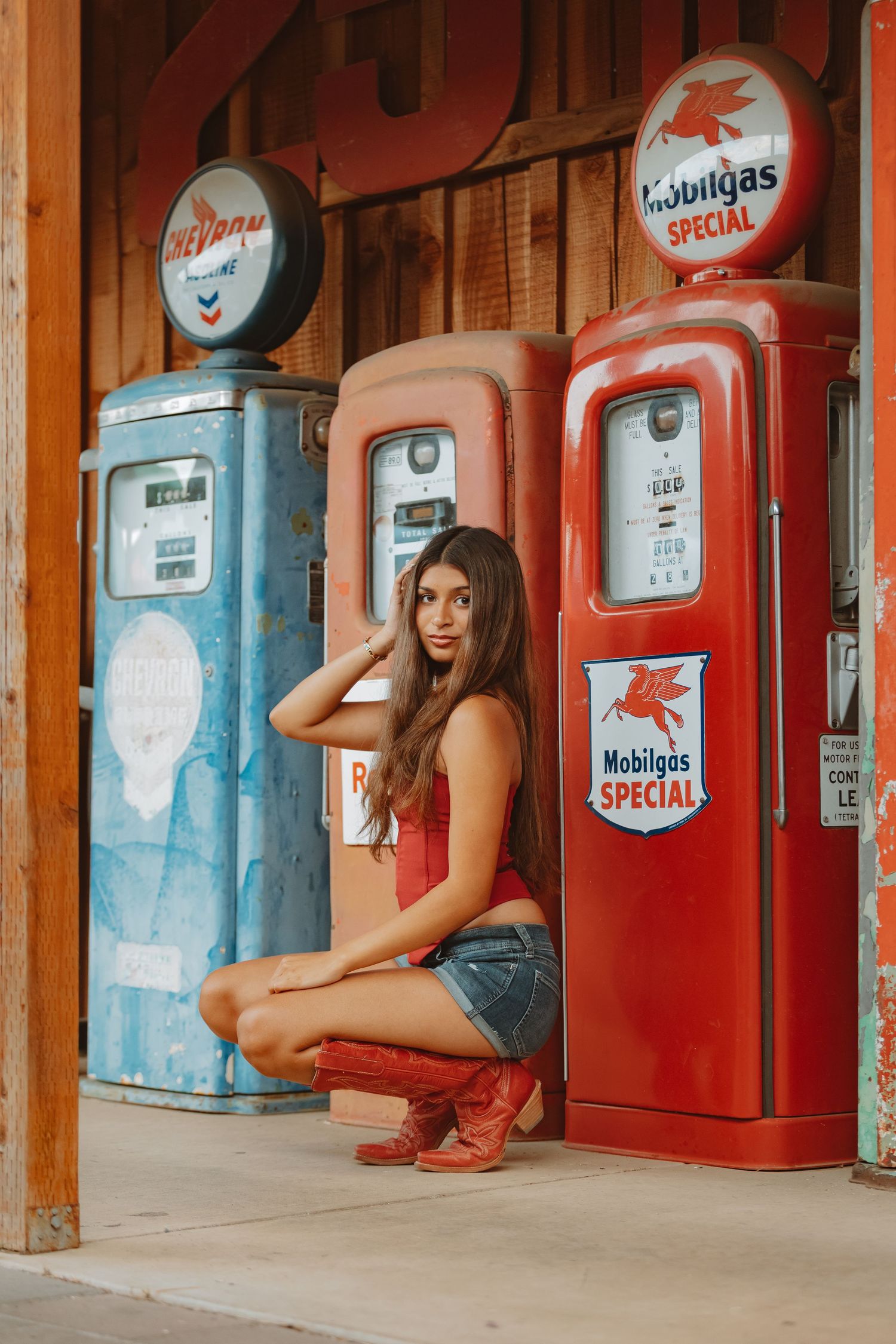 Casual summer outfit photographed at nostalgic gas station with vintage Mobilgas pumps.