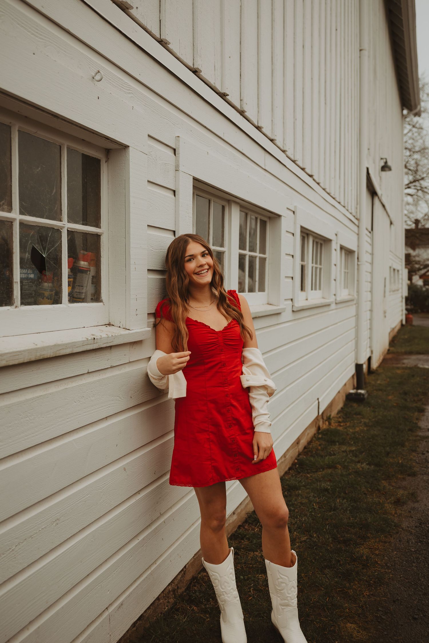 Woman in red romper strikes dynamic poses against white exterior wall.