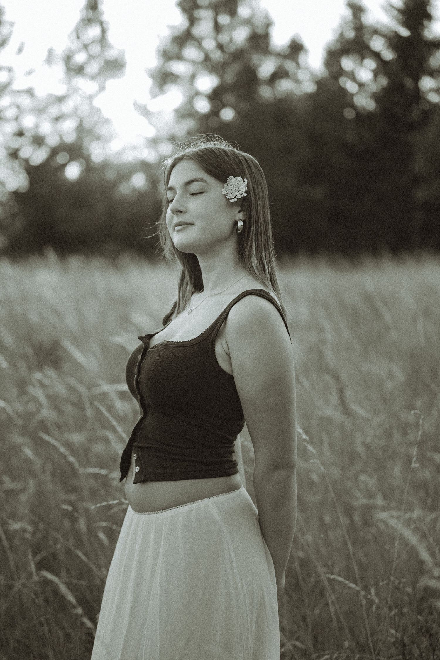 Black and white portrait showing a serene moment in a summer field with delicate floral accessories.