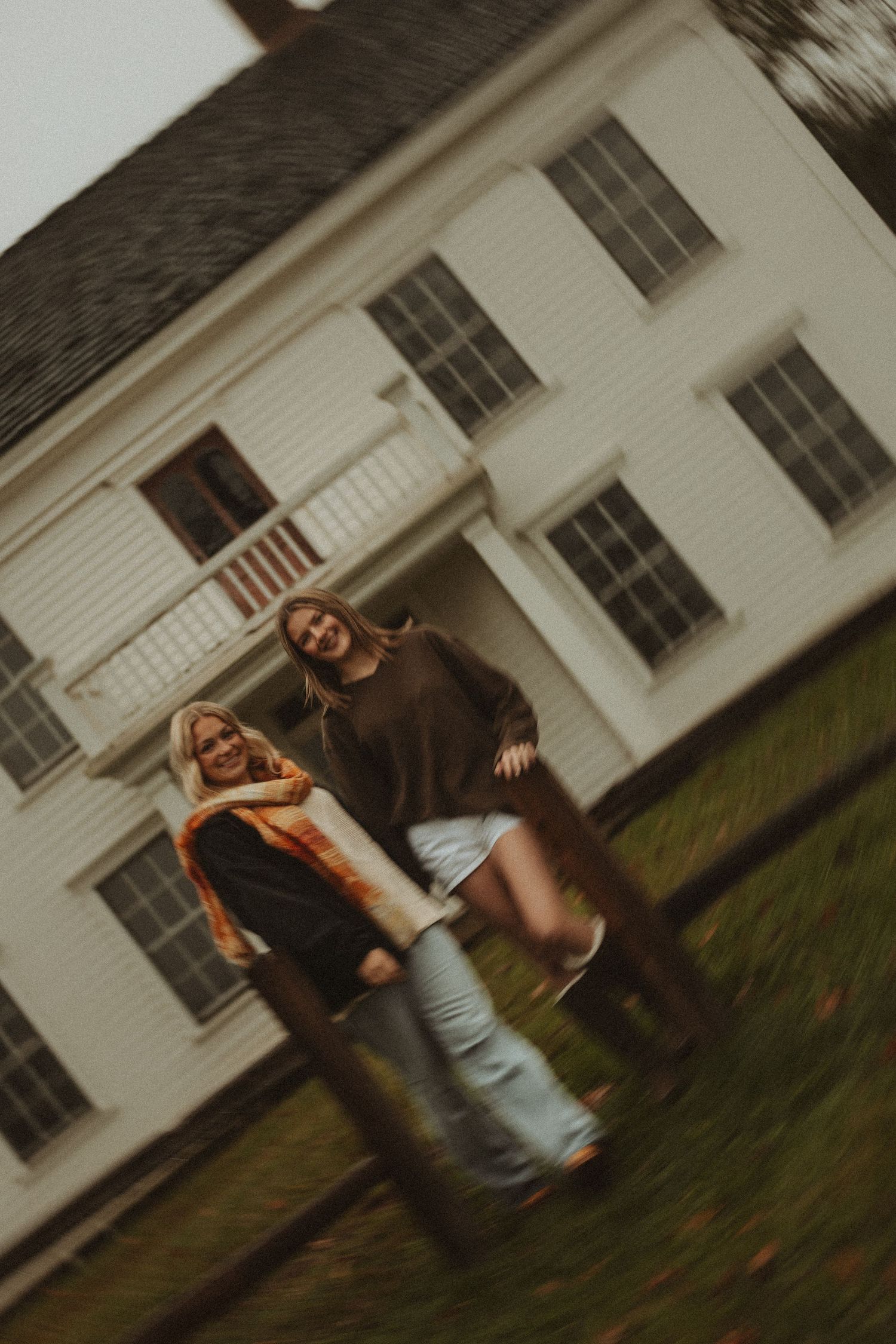 Friends in casual autumn outfits standing together against white farmhouse exterior.