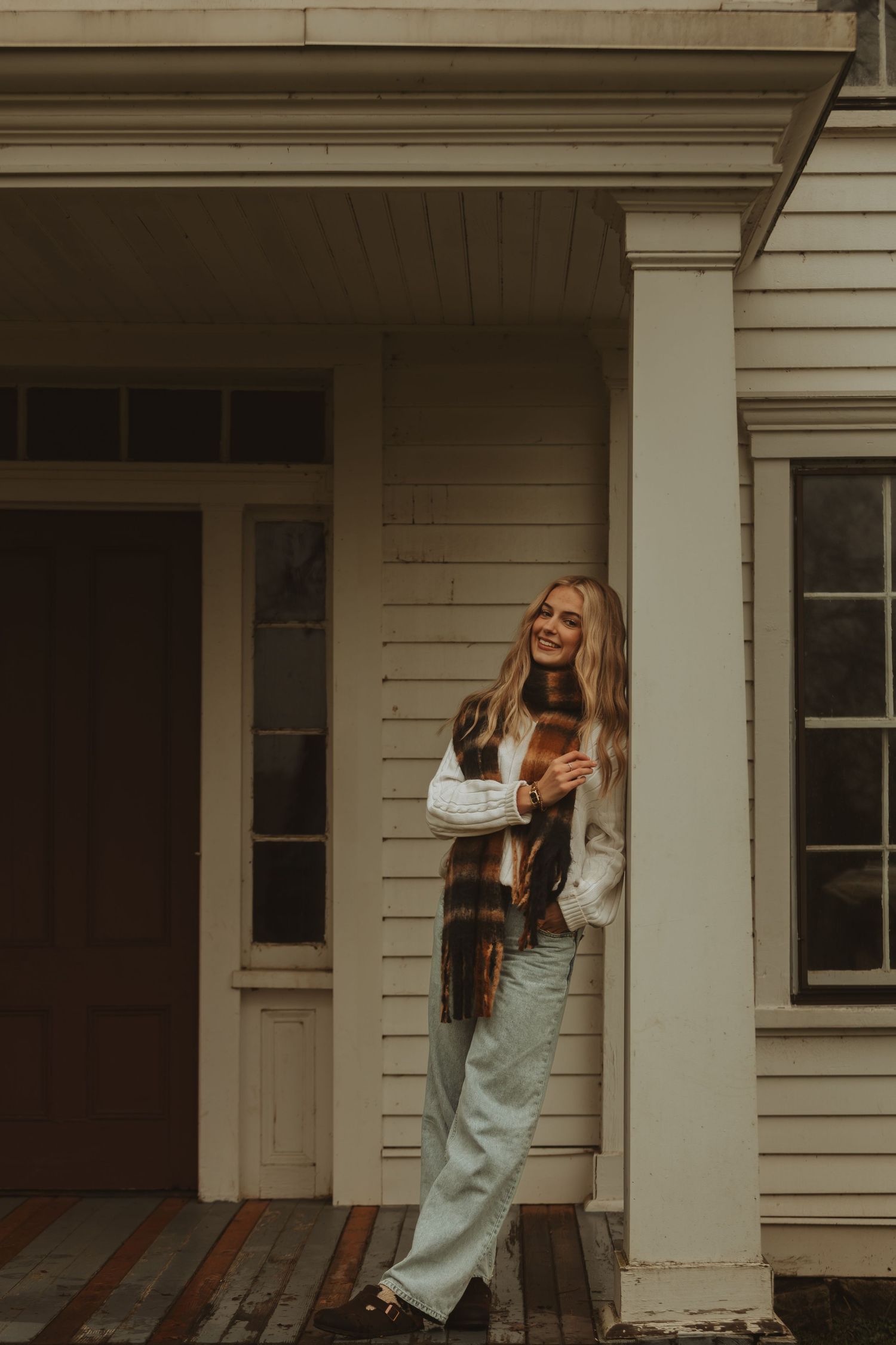 Friends enjoying autumn on a white porch with playful poses and laughter.
