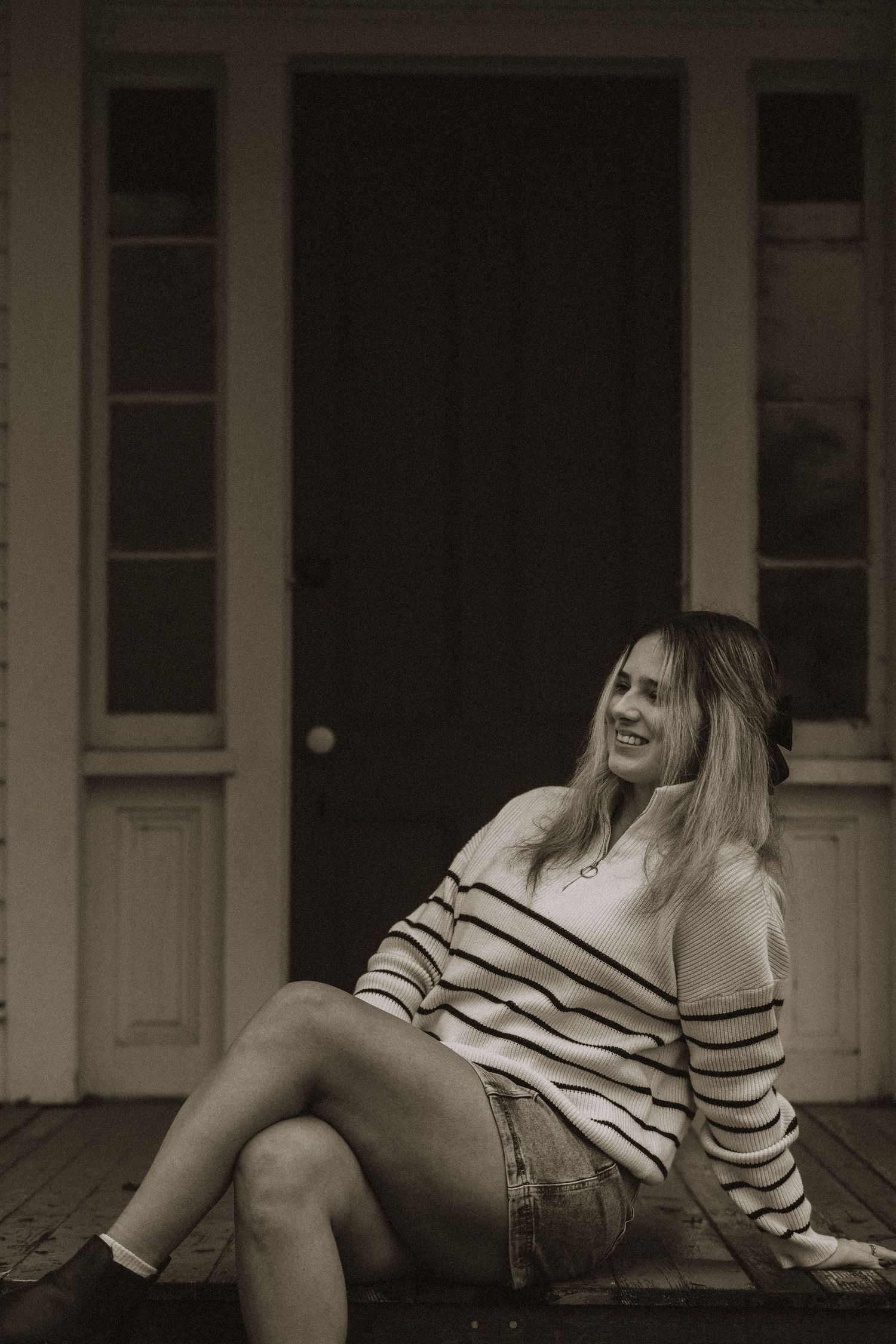 A person in striped clothing lounges on a porch in black and white photography.