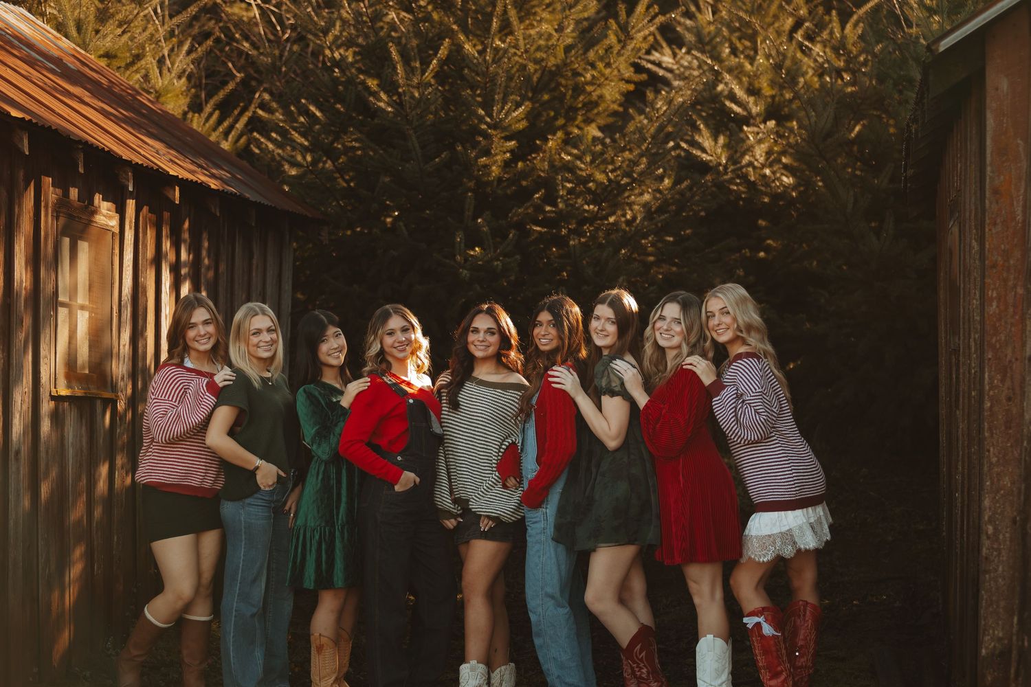 A group of people wearing formal attire stand together in a rustic wooden barn setting with warm lighting.