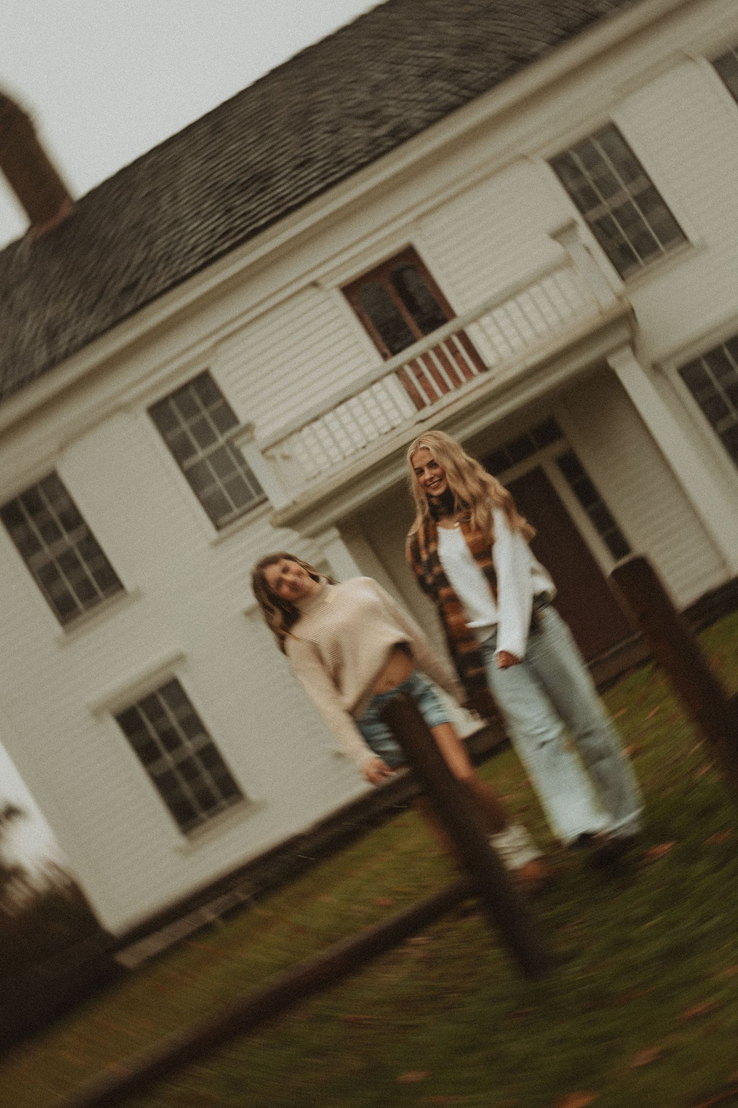 Three people laughing and having fun together outside a white building on a cloudy day.
