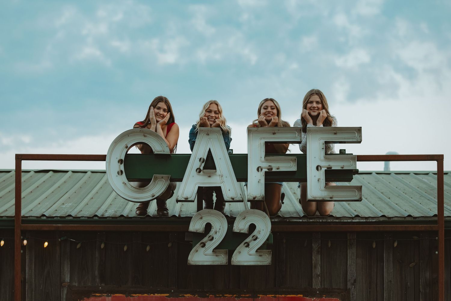 Weathered wooden building with vintage Cafe signage against blue sky.