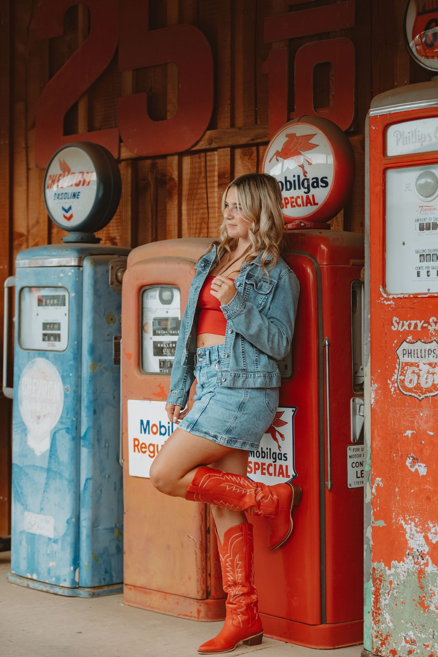 Stylish western-themed photo with red boots against classic Mobilgas pumps and rustic backdrop.