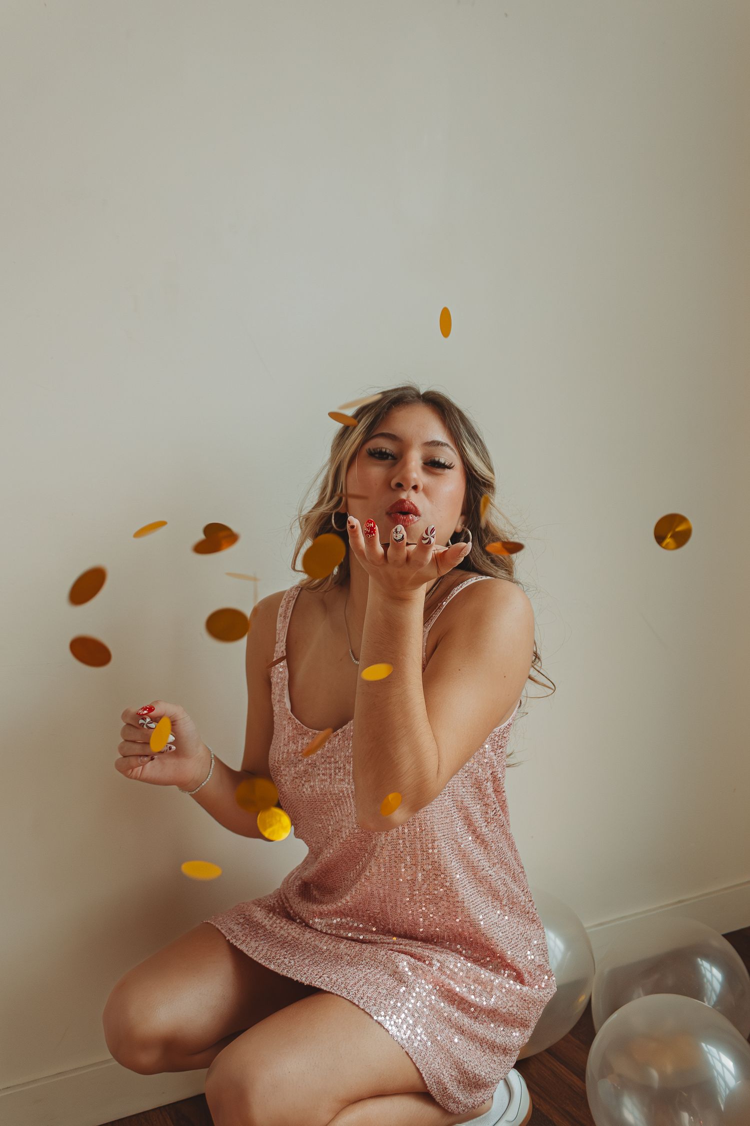 Person in pink sequin dress playfully tosses goldfish crackers in a fun photo sequence against white wall.