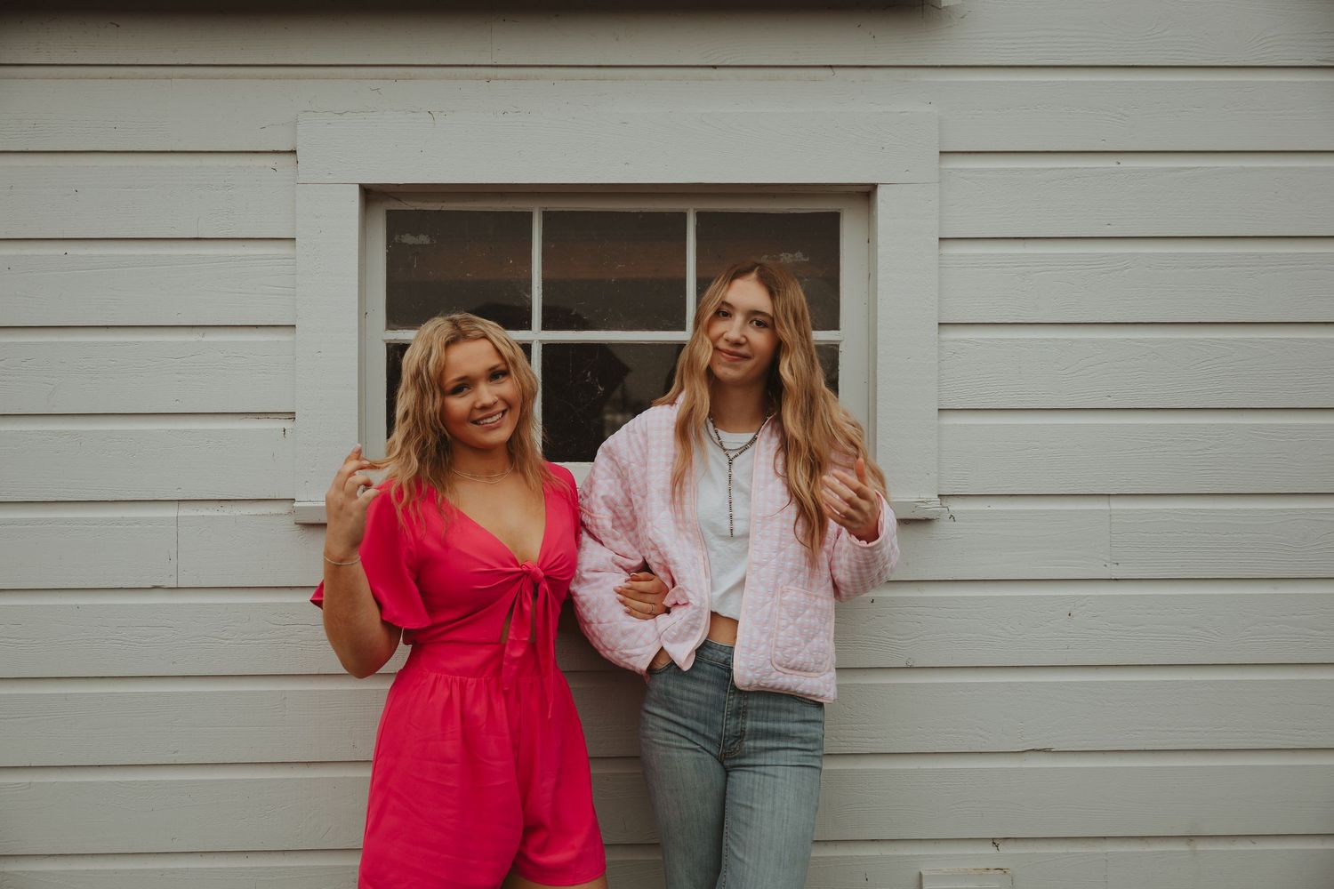 Lifestyle fashion shoot with pink and denim outfits against white wooden wall backdrop.