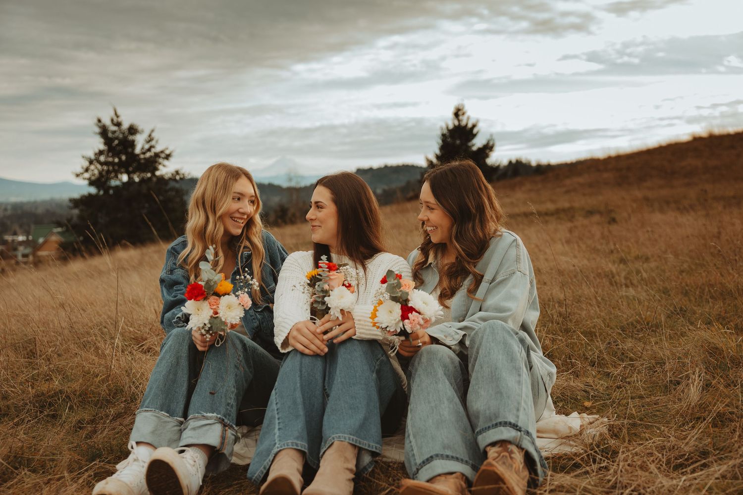 Friends gather together on a hillside sharing joyful moments in coordinated casual outfits.