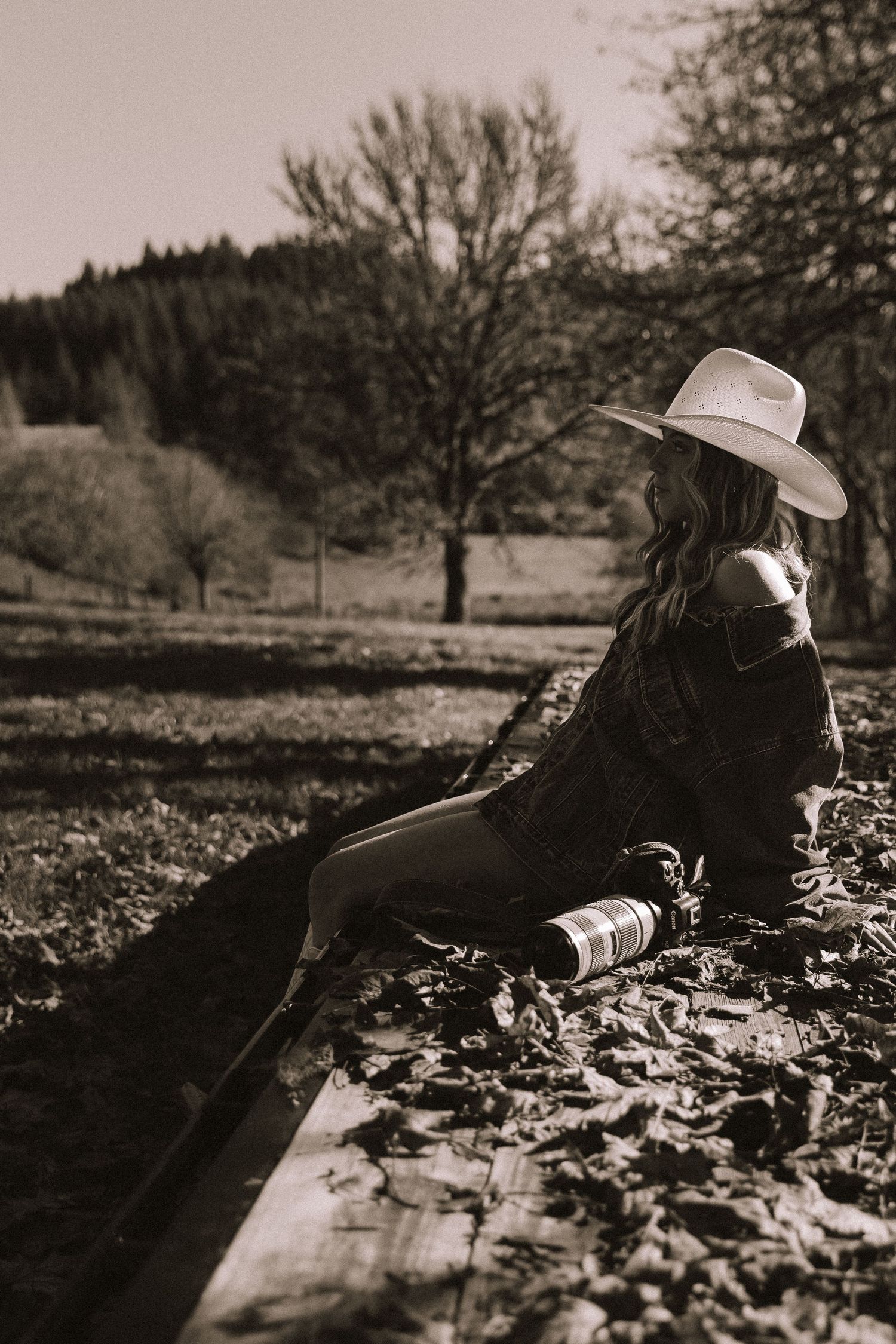 A person wearing a hat lies on fallen leaves in a black and white artistic photograph with multiple frames.