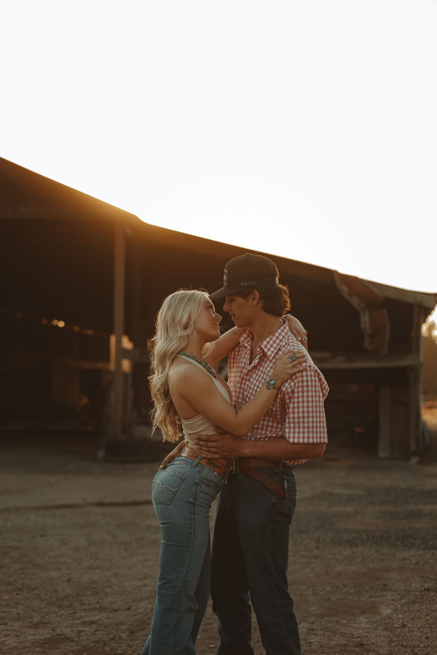 A couple shares an intimate moment at sunset wearing matching western-inspired outfits.