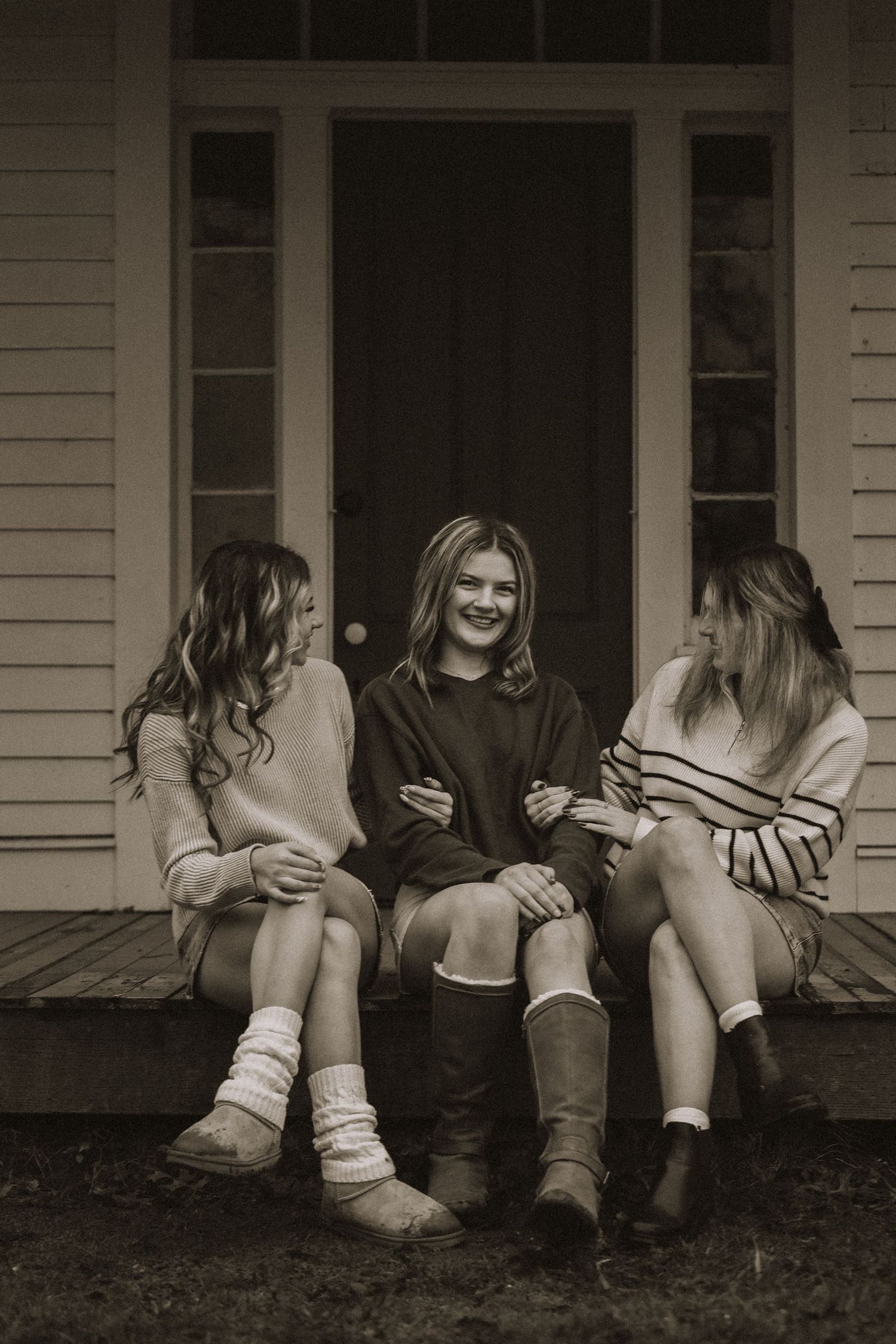 Group sitting on wooden porch steps in casual clothes with cozy socks.