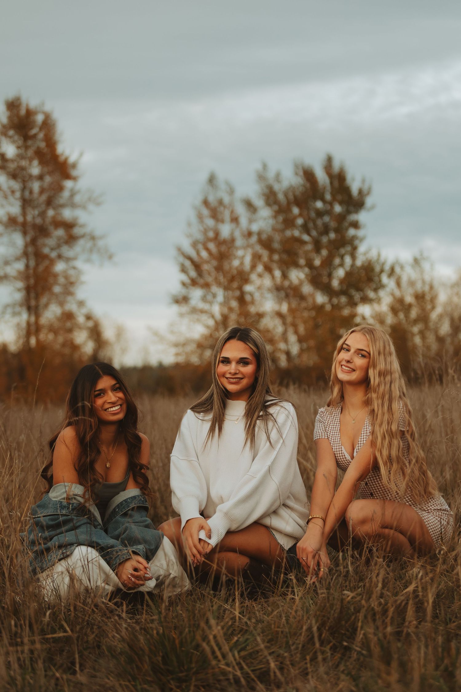Friends lying together in tall grass during golden hour creating candid moments.