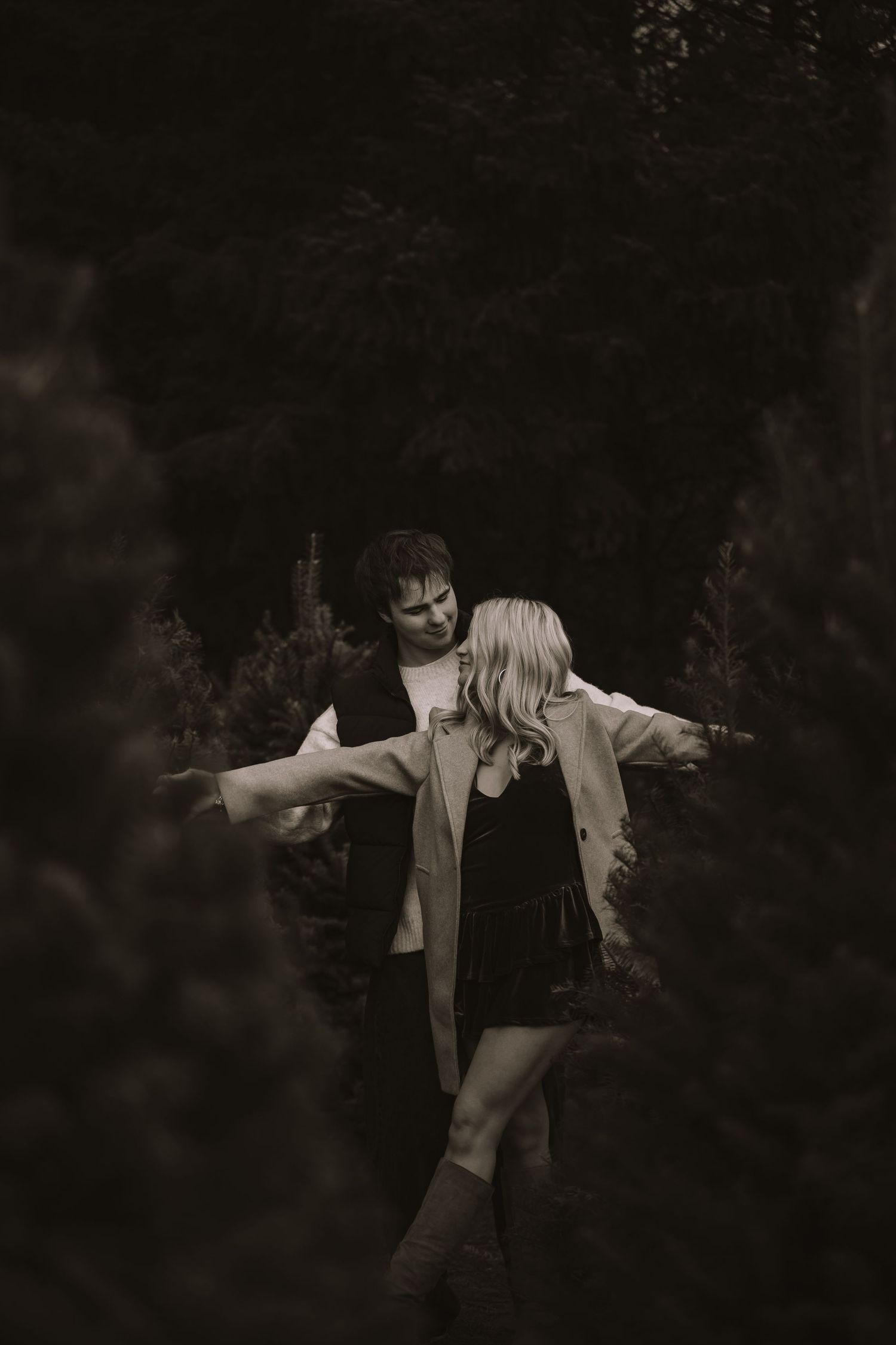 Artistic black and white photo of a couple enjoying a carefree moment in nature.