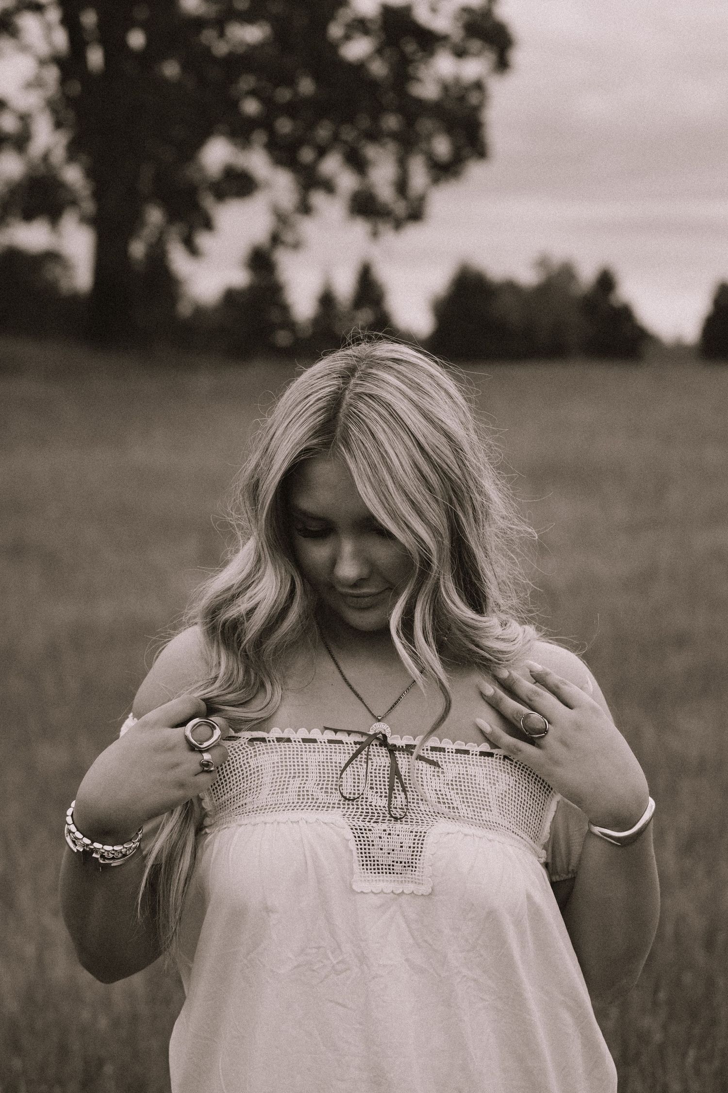 Black and white artistic portrait series showing a person in a white top posing expressively in a field.