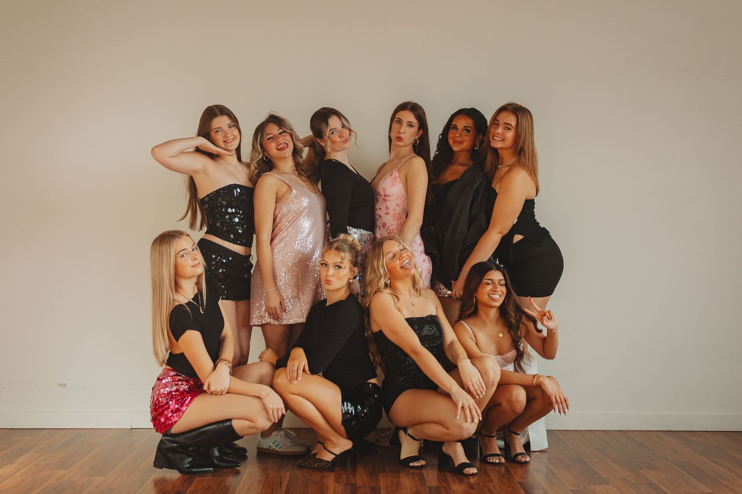 A group of women posing together in casual attire for a professional photoshoot against a neutral wall.