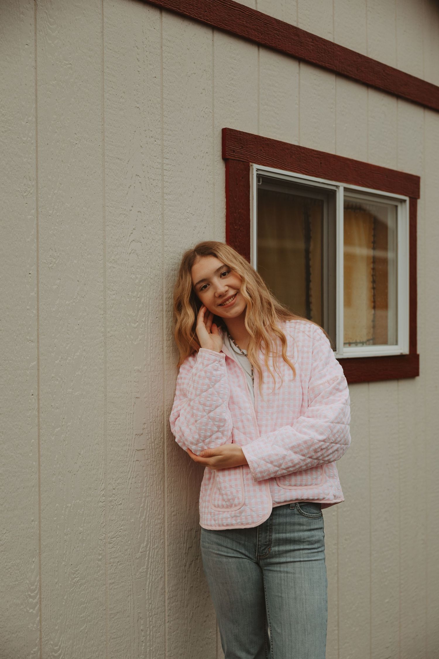 Woman in pink polka dot top and jeans poses playfully against beige wall in multiple candid shots.