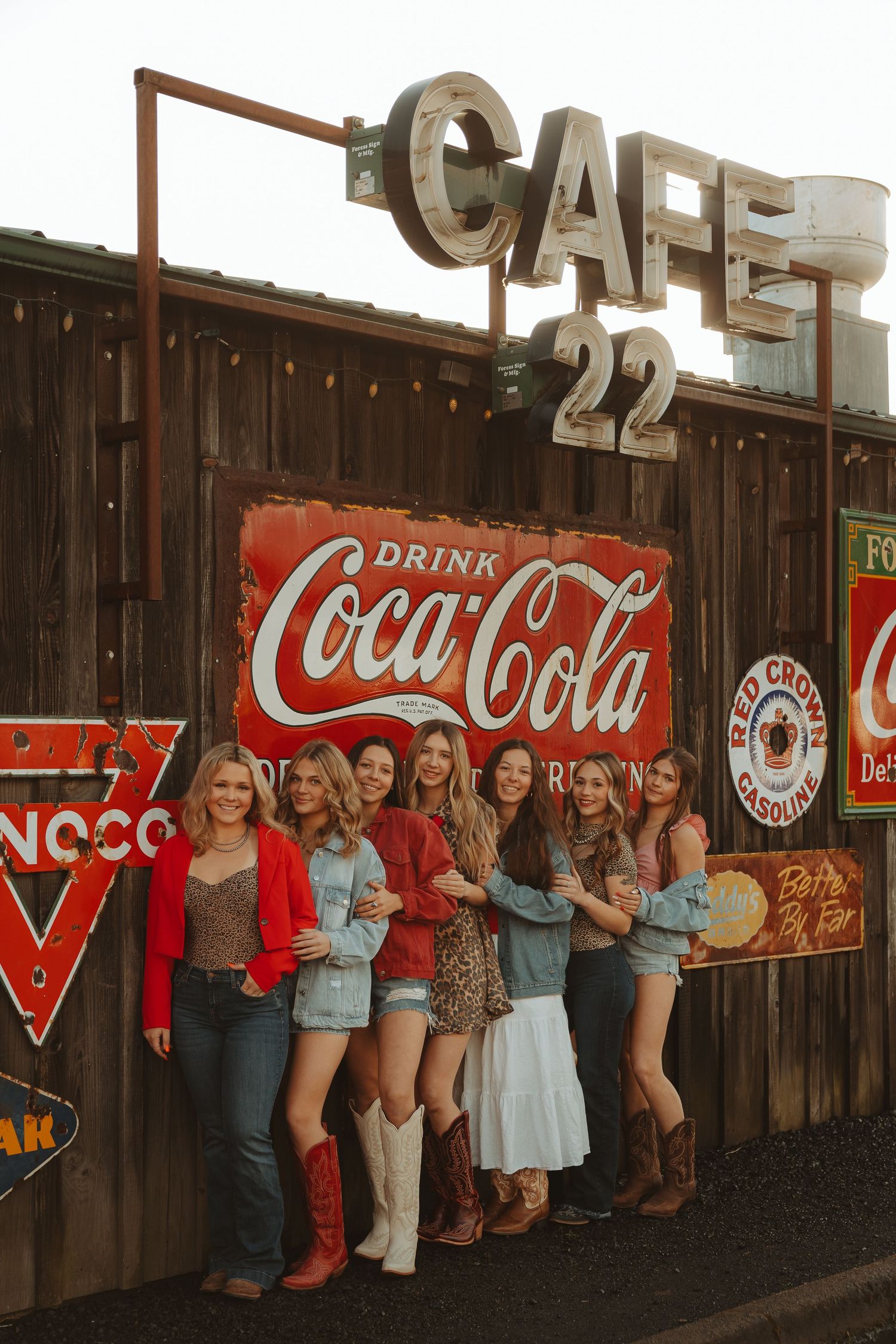 Group of women in western outfits posing in front of vintage Coca-Cola signs at Cafe 22.