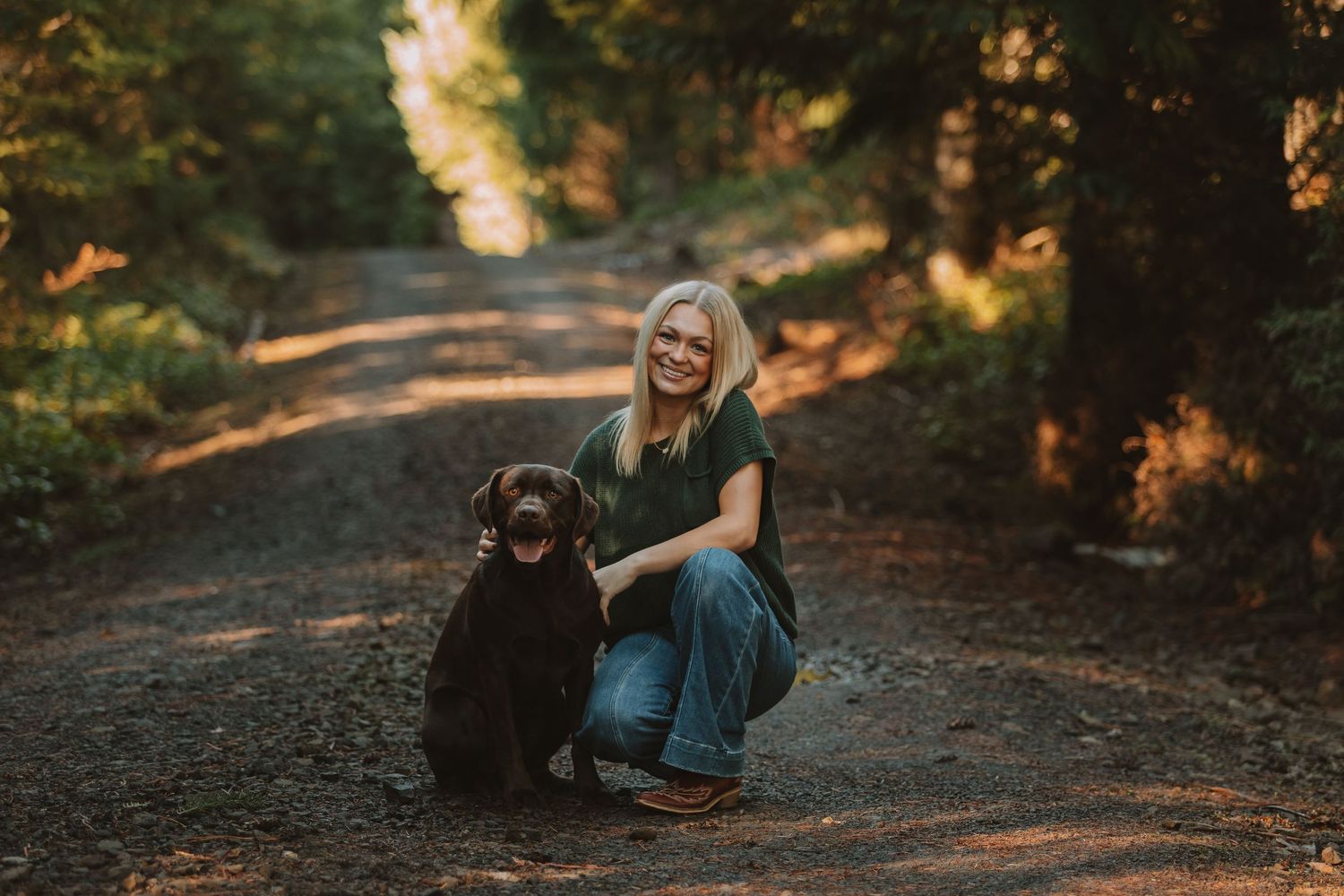 Couple laughing and embracing on a forest trail illuminated by warm autumn sunlight.