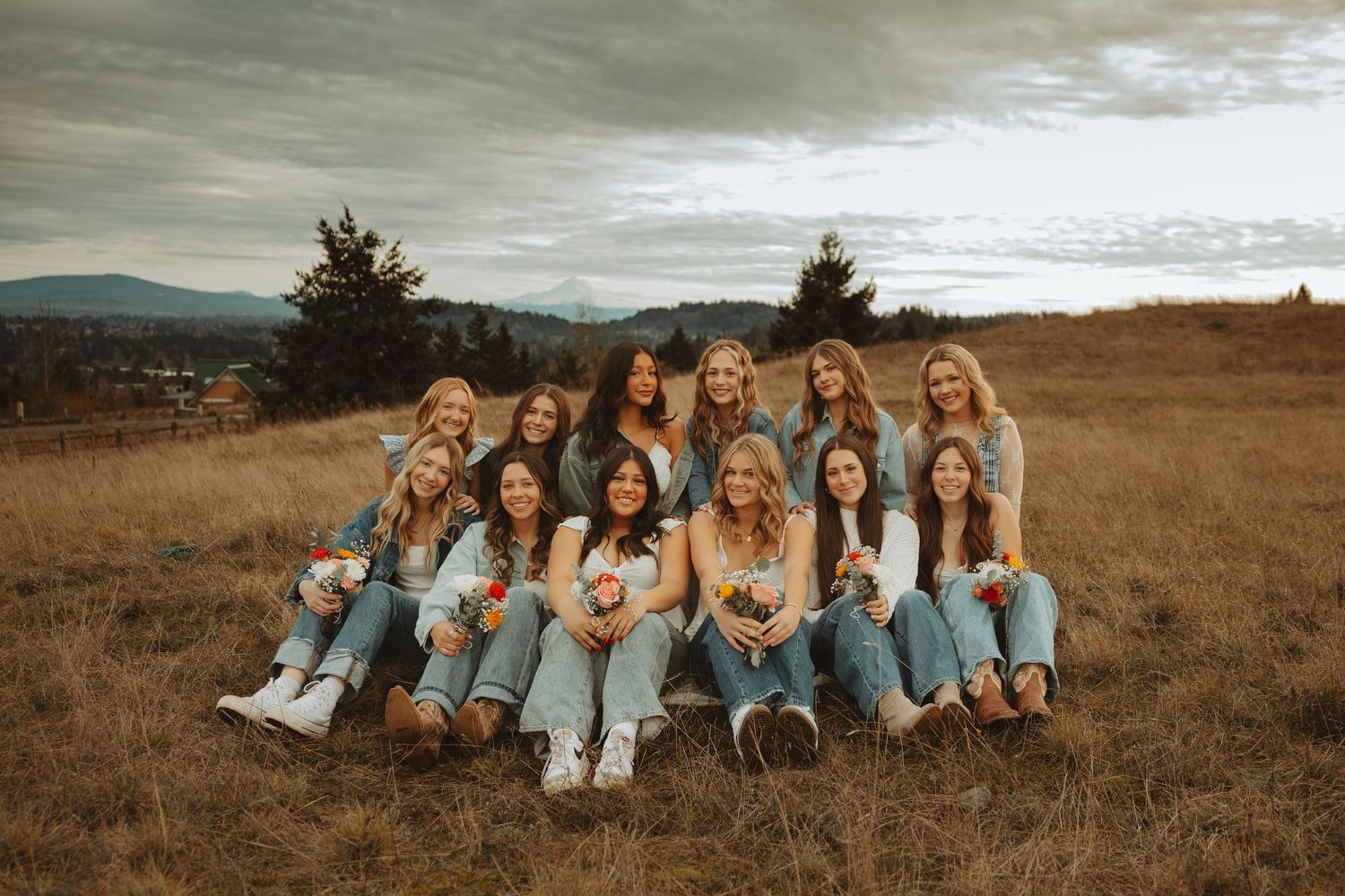 Group of friends in denim and white outfits lounging together in a golden autumn field at sunset.
