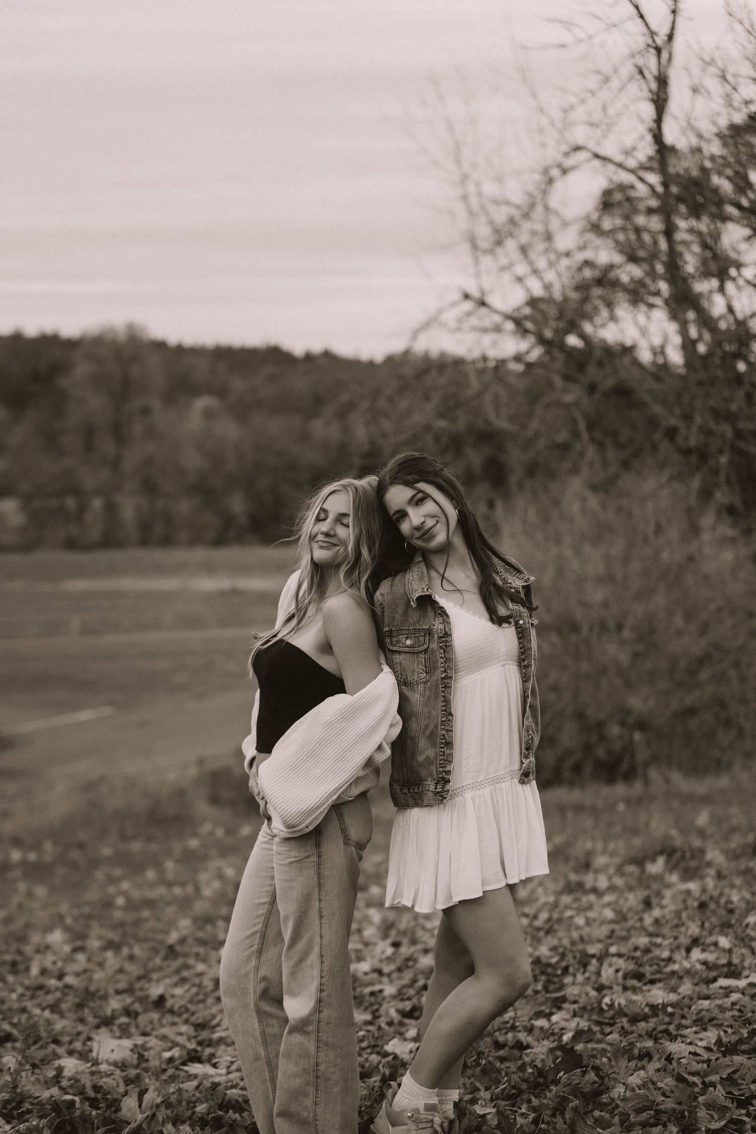 Friends in casual outfits laugh together in black and white photography.