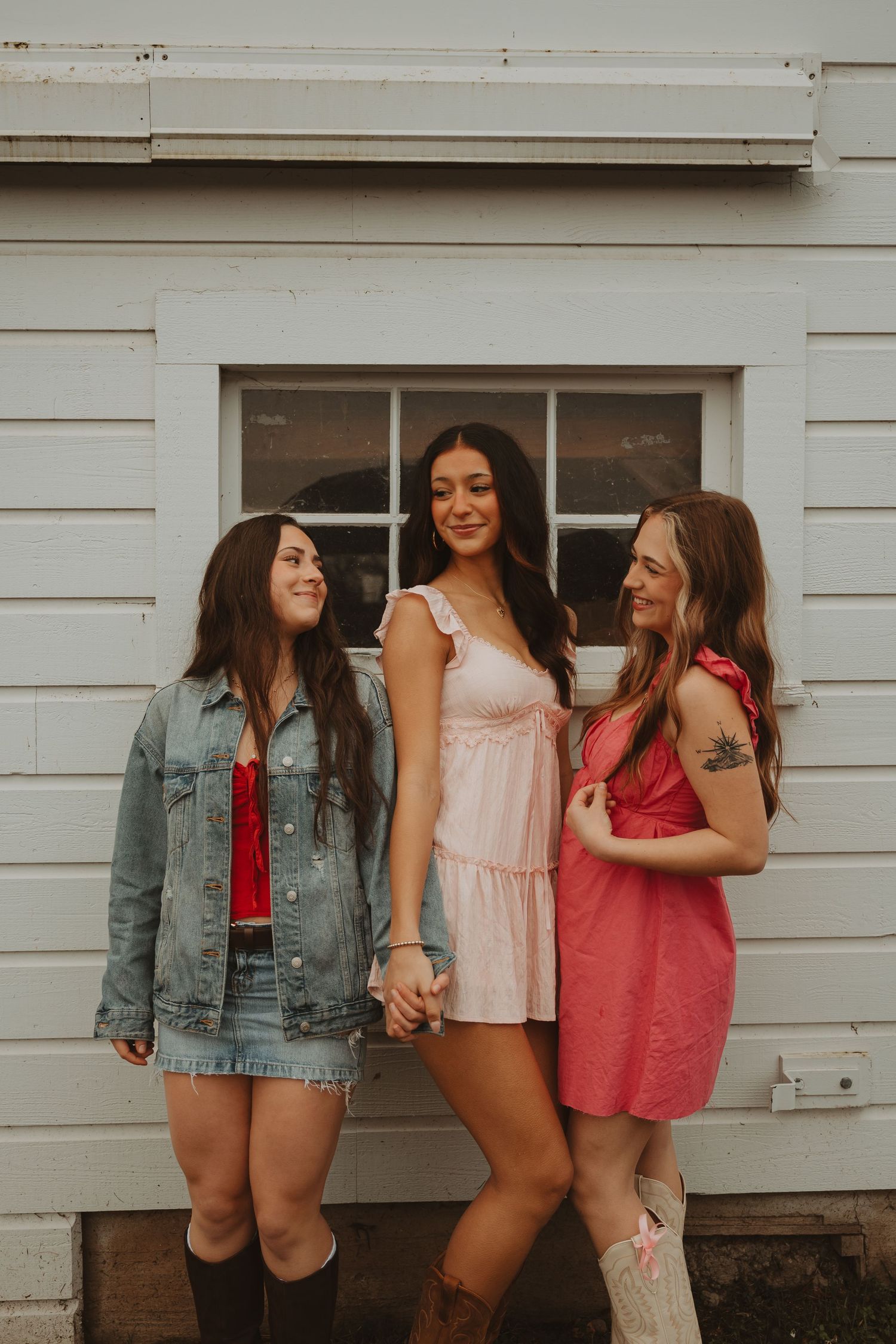 Group of friends in casual summer attire pose together by white building exterior.
