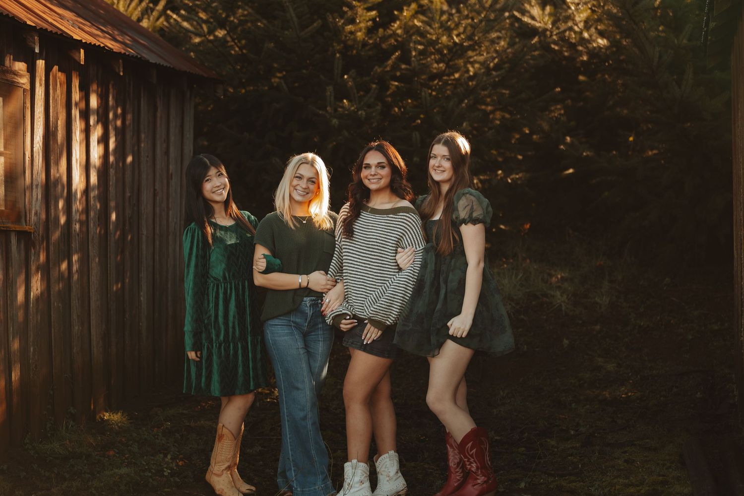 A group of people in casual attire stand together in a wooded outdoor setting at golden hour.