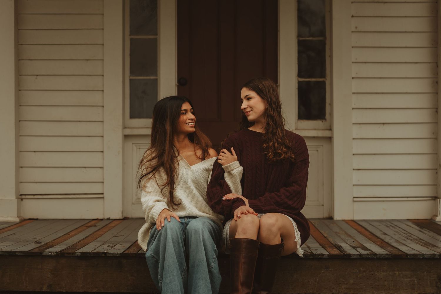 A couple sits together on a wooden porch swing, sharing an intimate moment at sunset.