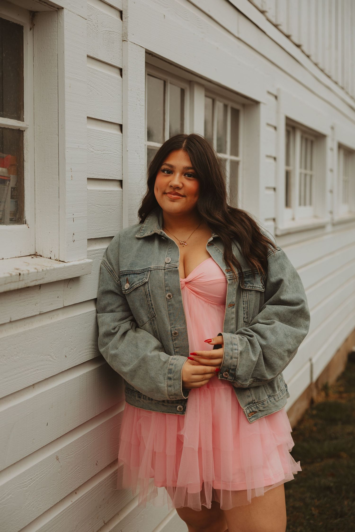 Fashion portrait against white wall featuring pink tulle skirt and denim jacket styling.
