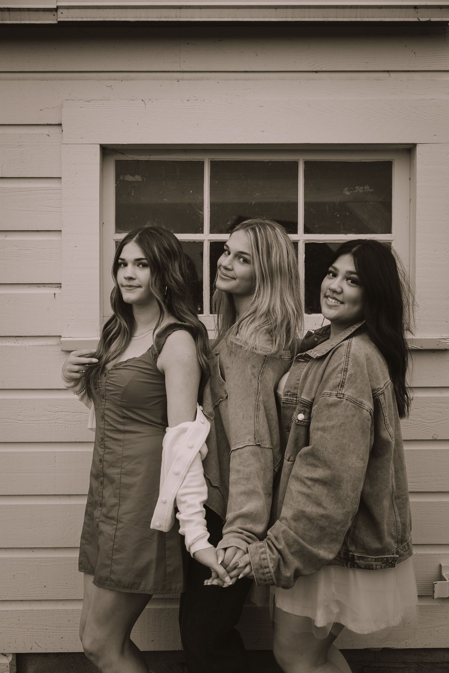 Friends in denim and casual wear pose together in black and white photo.