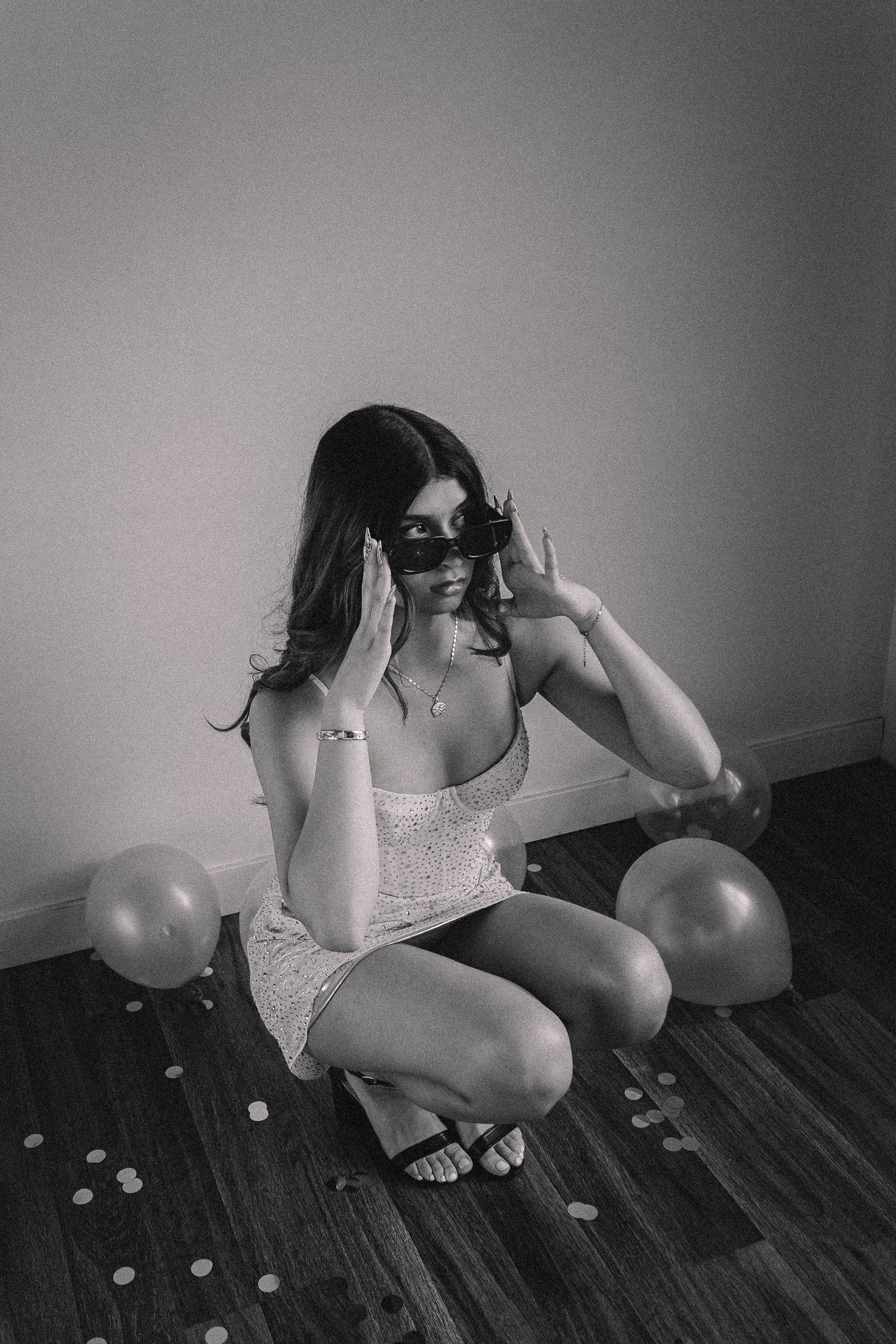 Black and white artistic photo series with balloons scattered on hardwood floor.