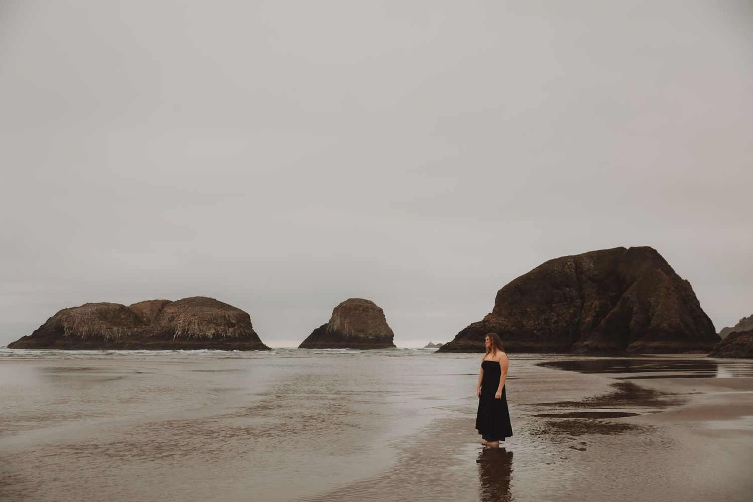 Dramatic coastal landscape with rocky cliffs and misty ocean waves crashing against the shore during overcast weather.