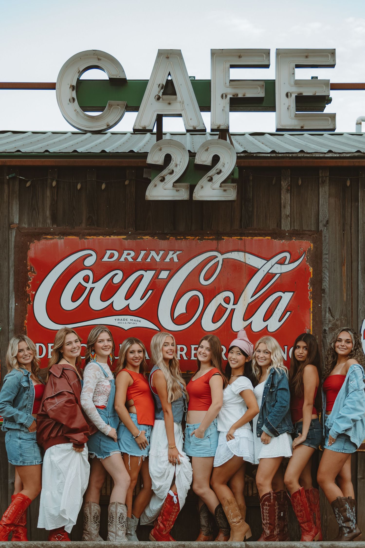 Group photo session in front of a rustic Coca-Cola cafe wall with vintage signage.